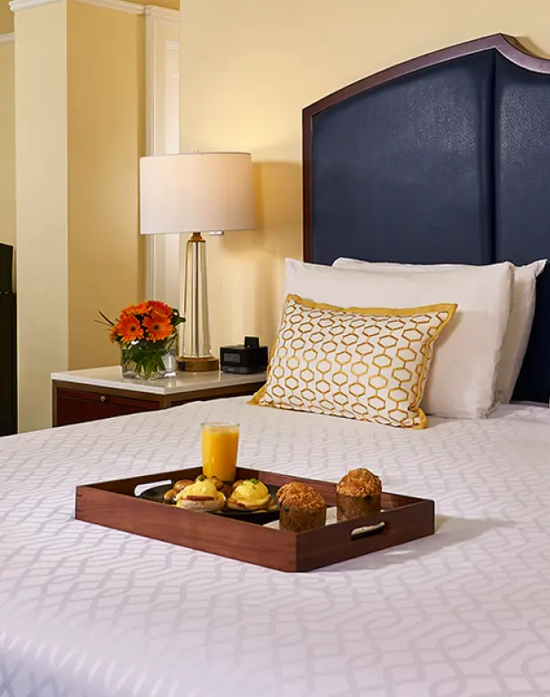 Food-on-the-bed-for-breakfast A hotel room with a king-sized bed with a tray of breakfast food and a small office area