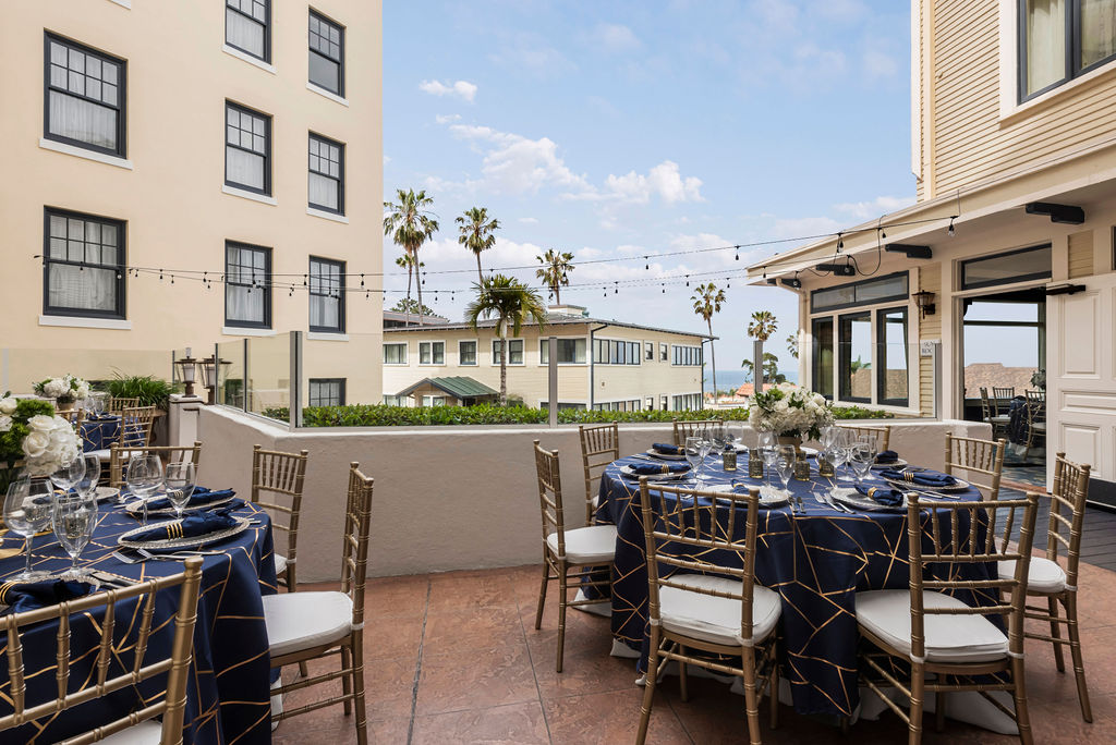 Grande-Colonial-Grande-Terrace-Banquet An outdoor patio with round dining room tables with a view of the surrounding building and the ocean between the buildings