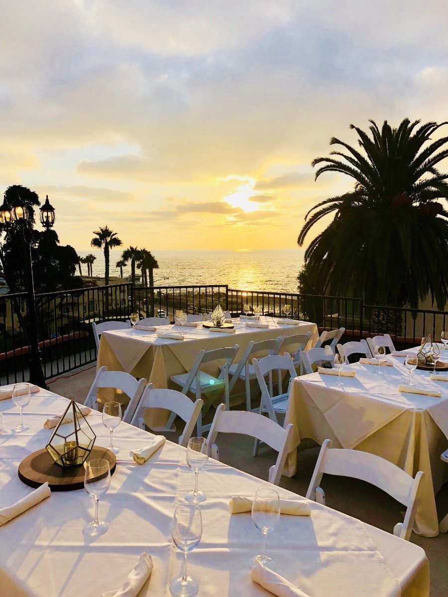 Grande-Colonial-Loft-Ocean-View-Rooftop-Deck A deck at sunset with three rectangular tables with the view of the ocean