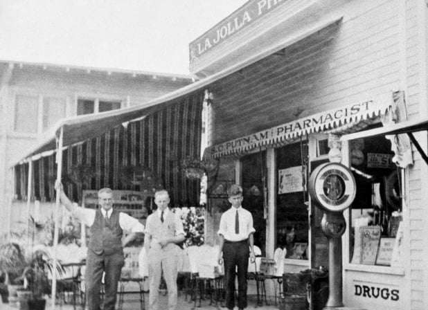 Silas Putnam with his son and another helper outside the Pharmacy (Colonial next door). Circa. 1920