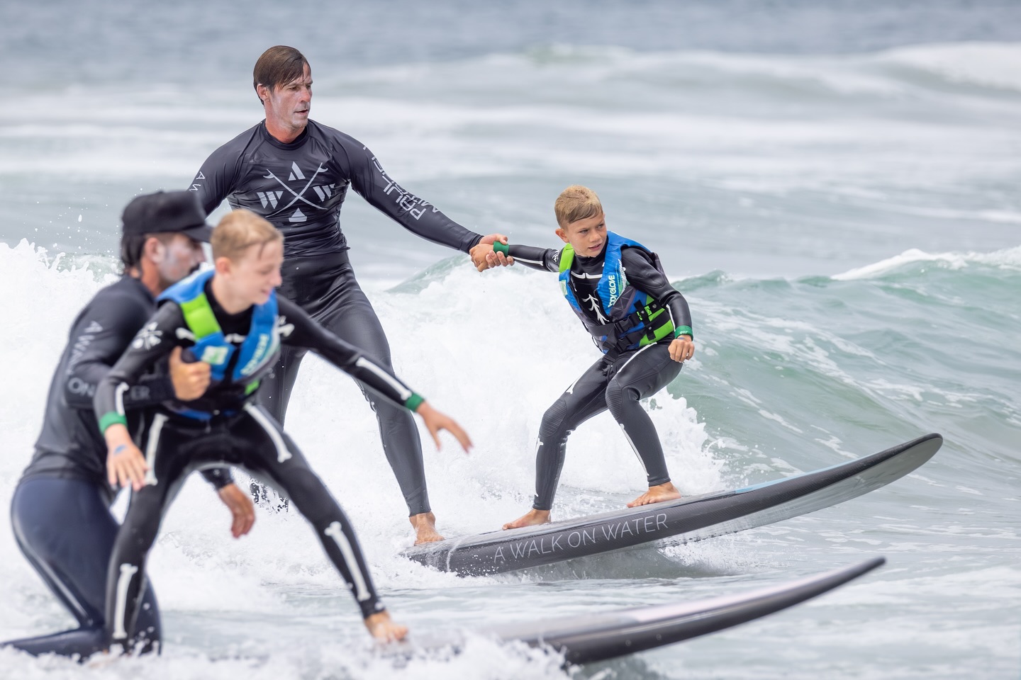 photo of two surfers teaching kids in water